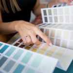 Close-up of two women choosing samples of wall paint Interior designer consulting a client looking at a color swatch House renovation concept - Dow Brothers Painting LTD
