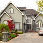 Large New House - Dow Brothers Painting LTD Front view of a large gray house with steep gables, arched windows, and a landscaped yard with a parked car in the driveway.